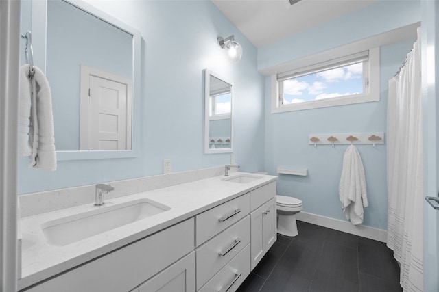 full bath featuring double vanity, toilet, baseboards, and a sink