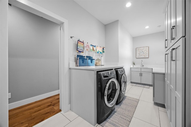 laundry room featuring cabinet space, a sink, recessed lighting, baseboards, and washer and clothes dryer