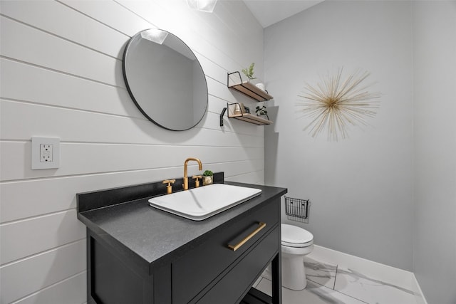 half bath featuring wood walls, vanity, baseboards, toilet, and marble finish floor
