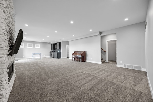 living area featuring light colored carpet, a fireplace, stairs, recessed lighting, and visible vents