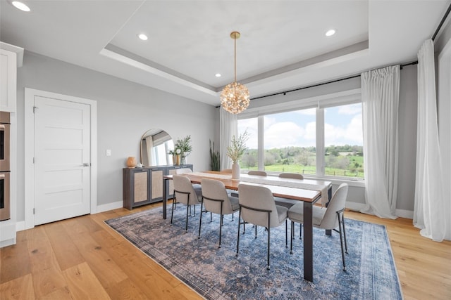 dining area with baseboards, light wood-style floors, recessed lighting, a tray ceiling, and a notable chandelier