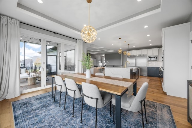 dining room featuring an inviting chandelier, a tray ceiling, and wood finished floors