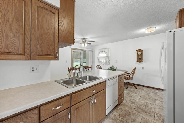 kitchen featuring white appliances, brown cabinets, a ceiling fan, and a sink