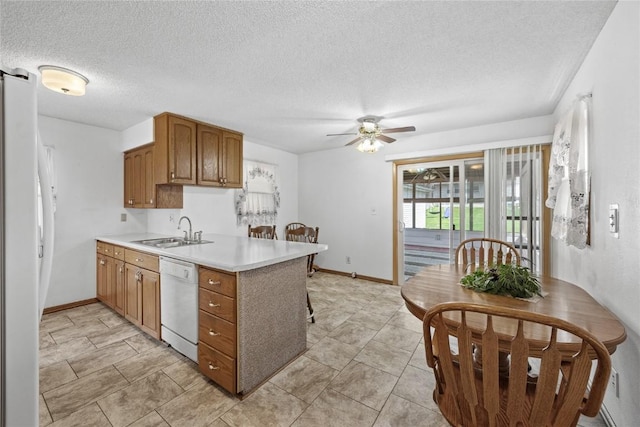 kitchen with a ceiling fan, a sink, light countertops, a peninsula, and white appliances