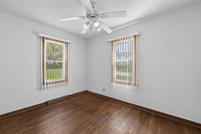 spare room with a ceiling fan, baseboards, visible vents, and dark wood-type flooring