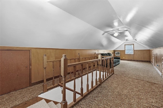 bonus room featuring ceiling fan, carpet, vaulted ceiling, and wood walls
