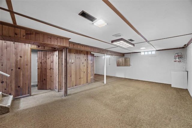 below grade area featuring wooden walls, visible vents, and carpet