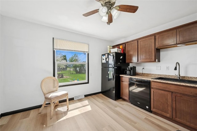 kitchen featuring visible vents, a sink, light wood-style flooring, and black appliances