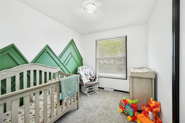 carpeted bedroom featuring a nursery area, baseboards, a textured ceiling, and visible vents