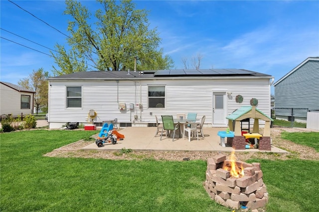 rear view of property with a lawn, a fire pit, solar panels, and a patio area