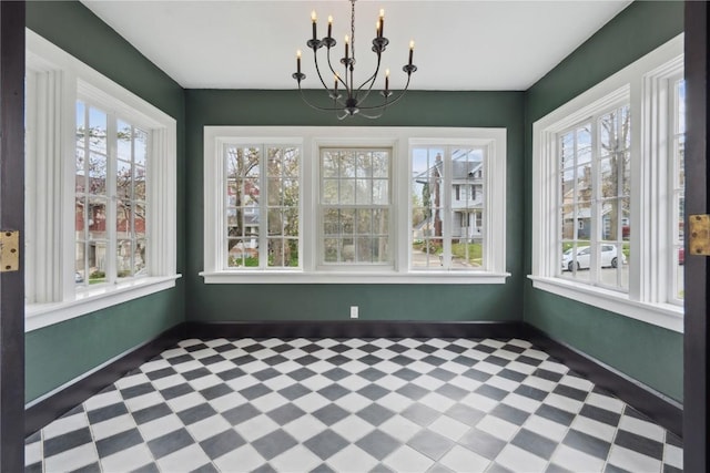 unfurnished dining area with baseboards, a wealth of natural light, tile patterned floors, and a notable chandelier