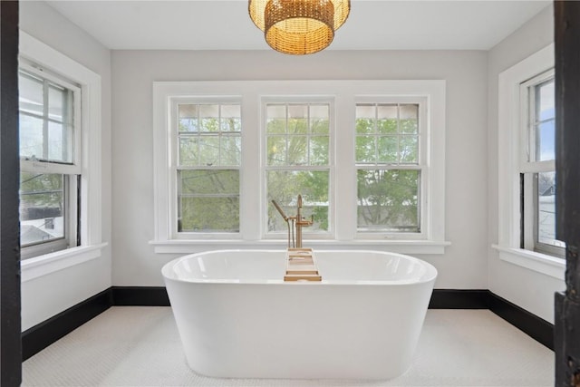bathroom with a soaking tub, baseboards, and a wealth of natural light