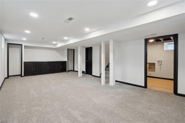 below grade area with visible vents, stairs, light carpet, baseboards, and recessed lighting