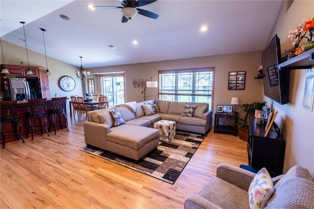 living room with recessed lighting, light wood finished floors, ceiling fan with notable chandelier, and lofted ceiling