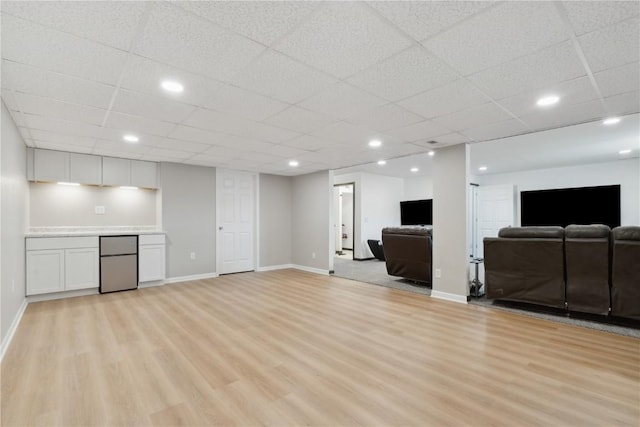unfurnished living room featuring light wood-type flooring, baseboards, and a drop ceiling