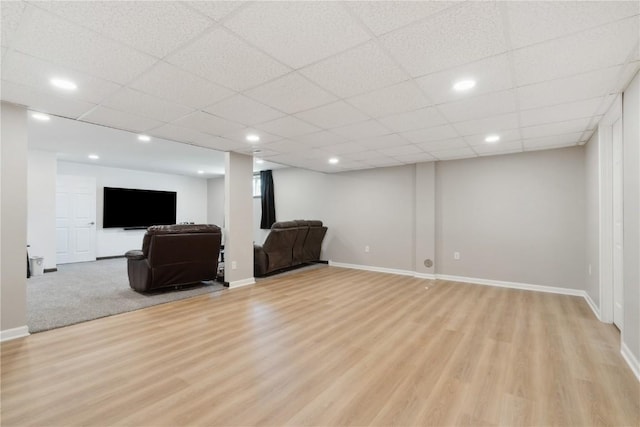 unfurnished living room featuring baseboards, recessed lighting, light wood-style flooring, and a drop ceiling