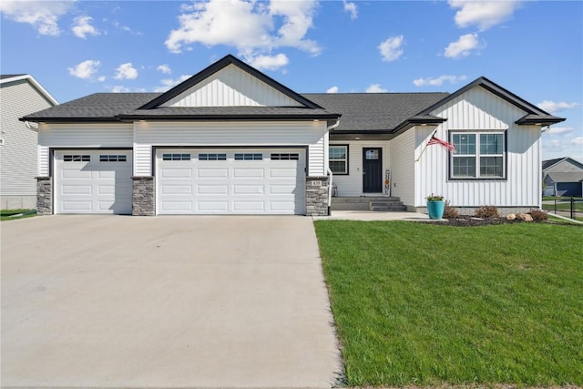 view of front of house featuring roof with shingles, an attached garage, a front lawn, board and batten siding, and driveway