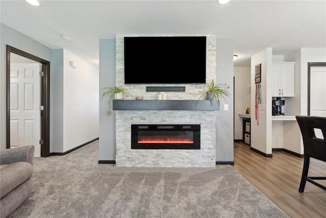living room featuring baseboards, recessed lighting, and a stone fireplace