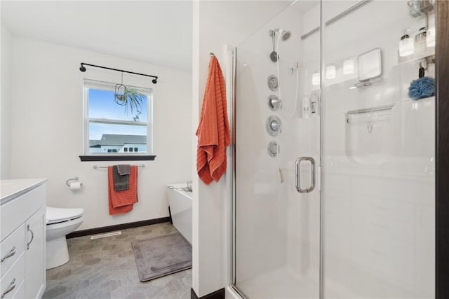 bathroom with vanity, toilet, a washtub, baseboards, and a stall shower