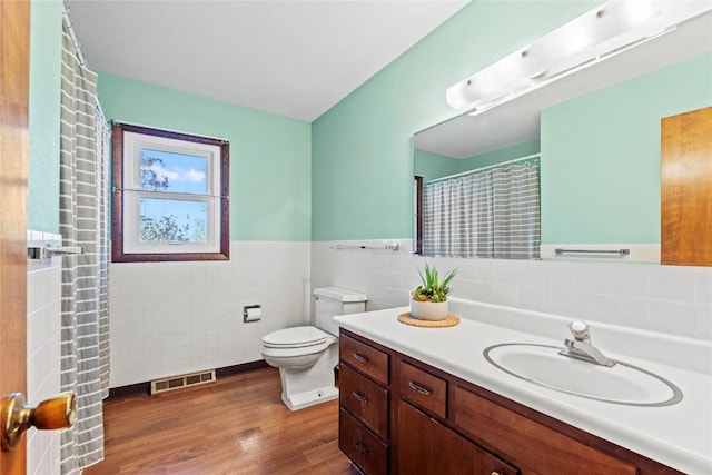 full bath featuring visible vents, tile walls, wood finished floors, vanity, and toilet