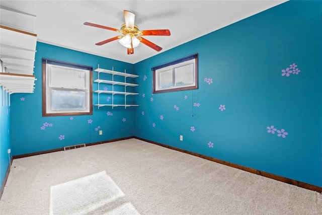 carpeted empty room featuring baseboards and a ceiling fan