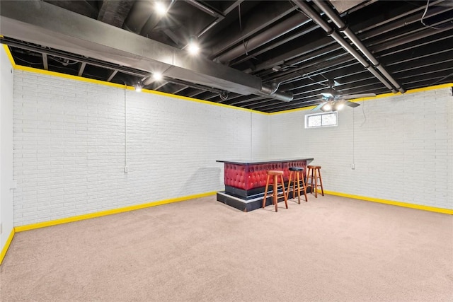 below grade area featuring a bar, carpet, baseboards, and brick wall