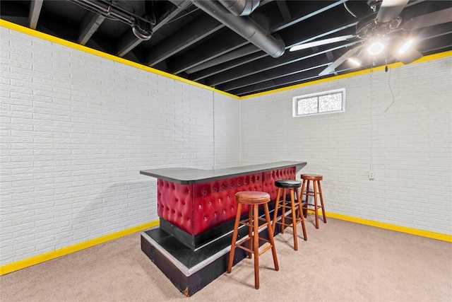 bar with baseboards, a bar, carpet flooring, and brick wall