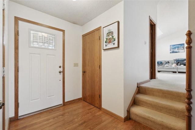 foyer with stairs, baseboards, and light wood-type flooring