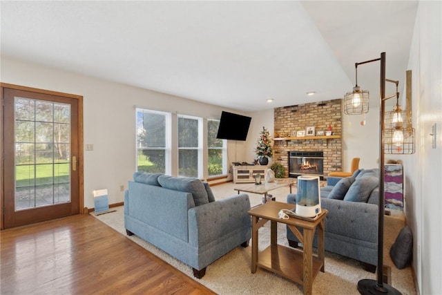 living room with baseboards, light wood finished floors, and a brick fireplace