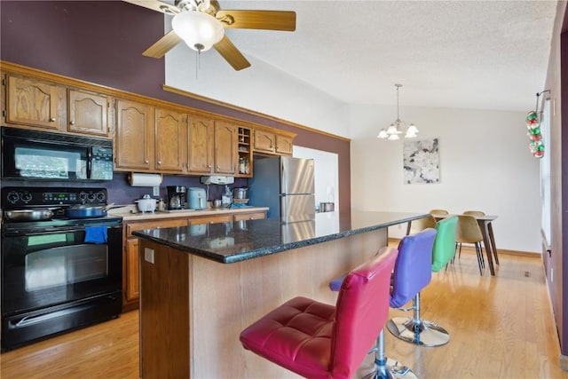 kitchen with brown cabinetry, light wood-style flooring, lofted ceiling, a kitchen bar, and black appliances