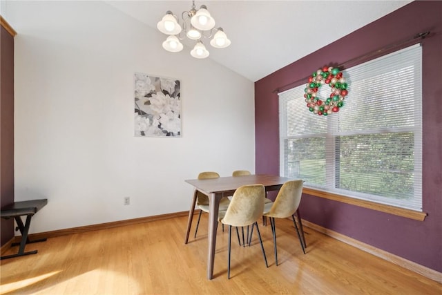 dining area with light wood-style floors, baseboards, a chandelier, and lofted ceiling