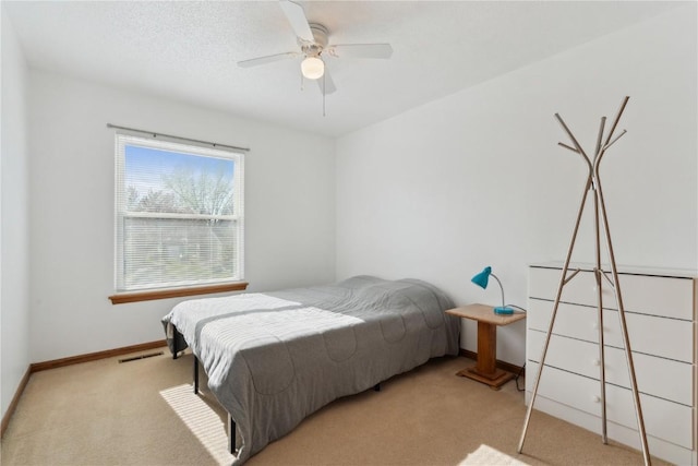 carpeted bedroom with baseboards, a ceiling fan, and visible vents