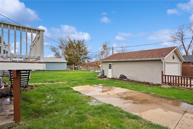 view of yard with a detached garage, fence, and an outbuilding