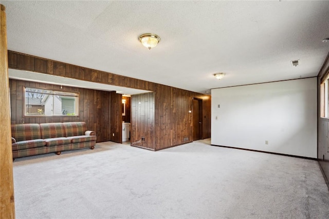 unfurnished living room with carpet, wood walls, and a textured ceiling