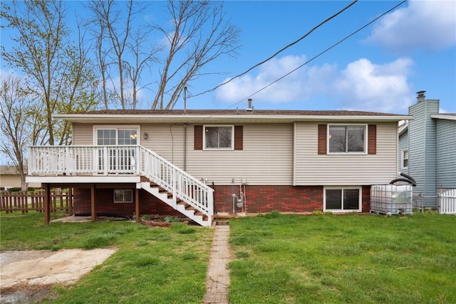 rear view of house with fence, a wooden deck, a yard, and stairway