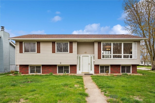 raised ranch featuring brick siding and a front lawn