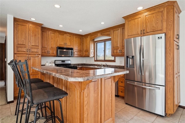 kitchen with recessed lighting, appliances with stainless steel finishes, brown cabinetry, and light tile patterned floors