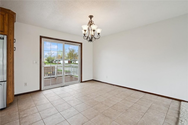 spare room with a textured ceiling, baseboards, and a chandelier