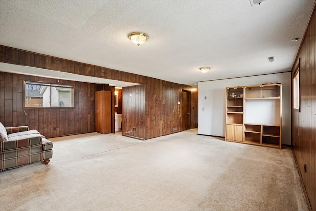 unfurnished living room featuring a textured ceiling, wooden walls, and light carpet