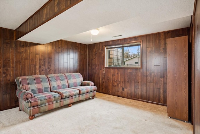 carpeted living room featuring wooden walls and visible vents