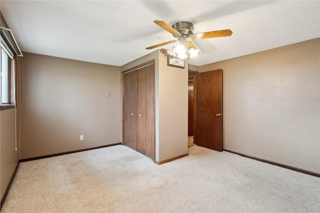 unfurnished bedroom with baseboards, ceiling fan, carpet, and a closet