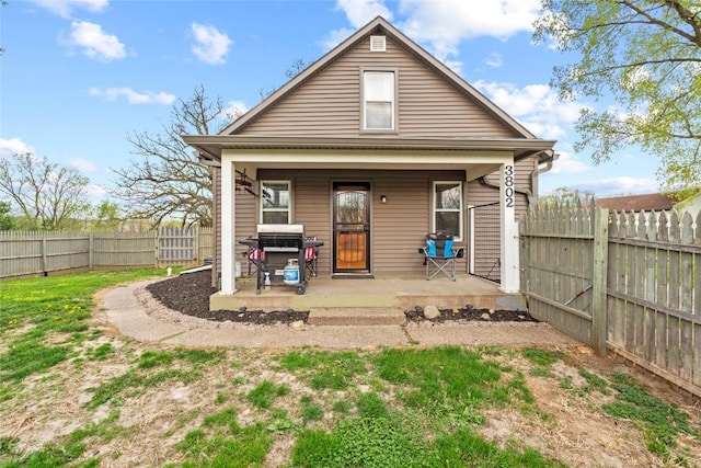 back of property with covered porch and a fenced backyard