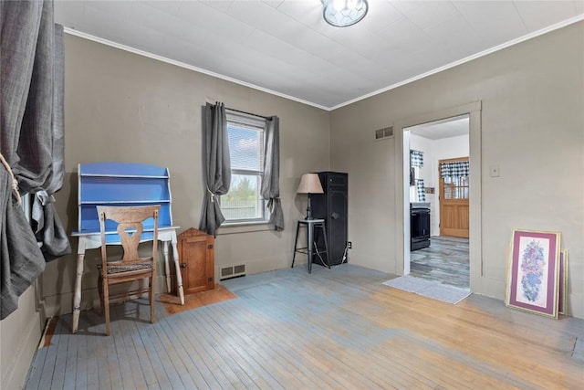interior space with visible vents, crown molding, and hardwood / wood-style flooring