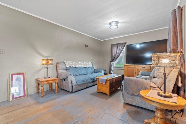 living area featuring light wood-style floors, ornamental molding, and visible vents