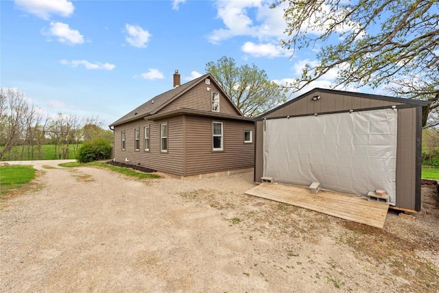 view of property exterior with an outdoor structure, a shed, and a chimney