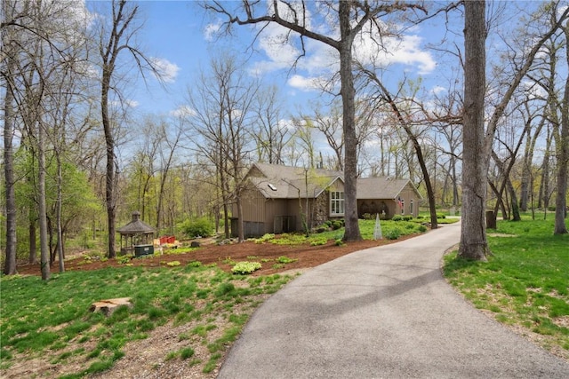 exterior space featuring board and batten siding, a gazebo, and aphalt driveway