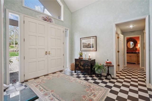 entrance foyer featuring tile patterned floors, baseboards, and high vaulted ceiling