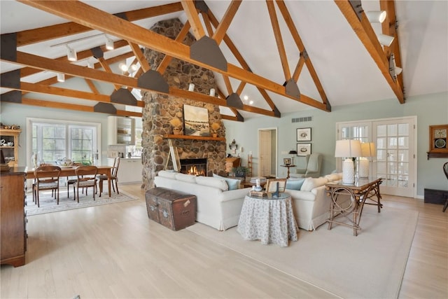 living area featuring beam ceiling, a fireplace, high vaulted ceiling, wood finished floors, and visible vents