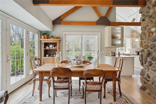dining room featuring light wood-style floors, high vaulted ceiling, and beamed ceiling