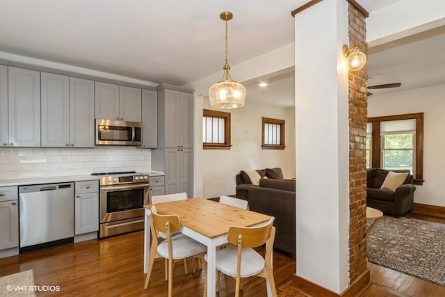 kitchen with dark wood-type flooring, appliances with stainless steel finishes, gray cabinetry, and tasteful backsplash